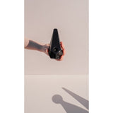 Hand holding Prism Ceramic Pipe, a black pyramid-shaped ceramic pipe designed for optimal airflow and comfort, enhancing both smoking experience and visual appeal.