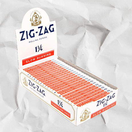 Zig-Zag 1 1/4 White Rolling Paper box, featuring iconic branding, highlighting thin, slow-burning papers made with natural gum Arabic for an enhanced smoking experience.