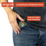 Person placing an Aluminum Storage Puck into a denim pocket, showcasing its compact size and discreet design for convenient, on-the-go storage.