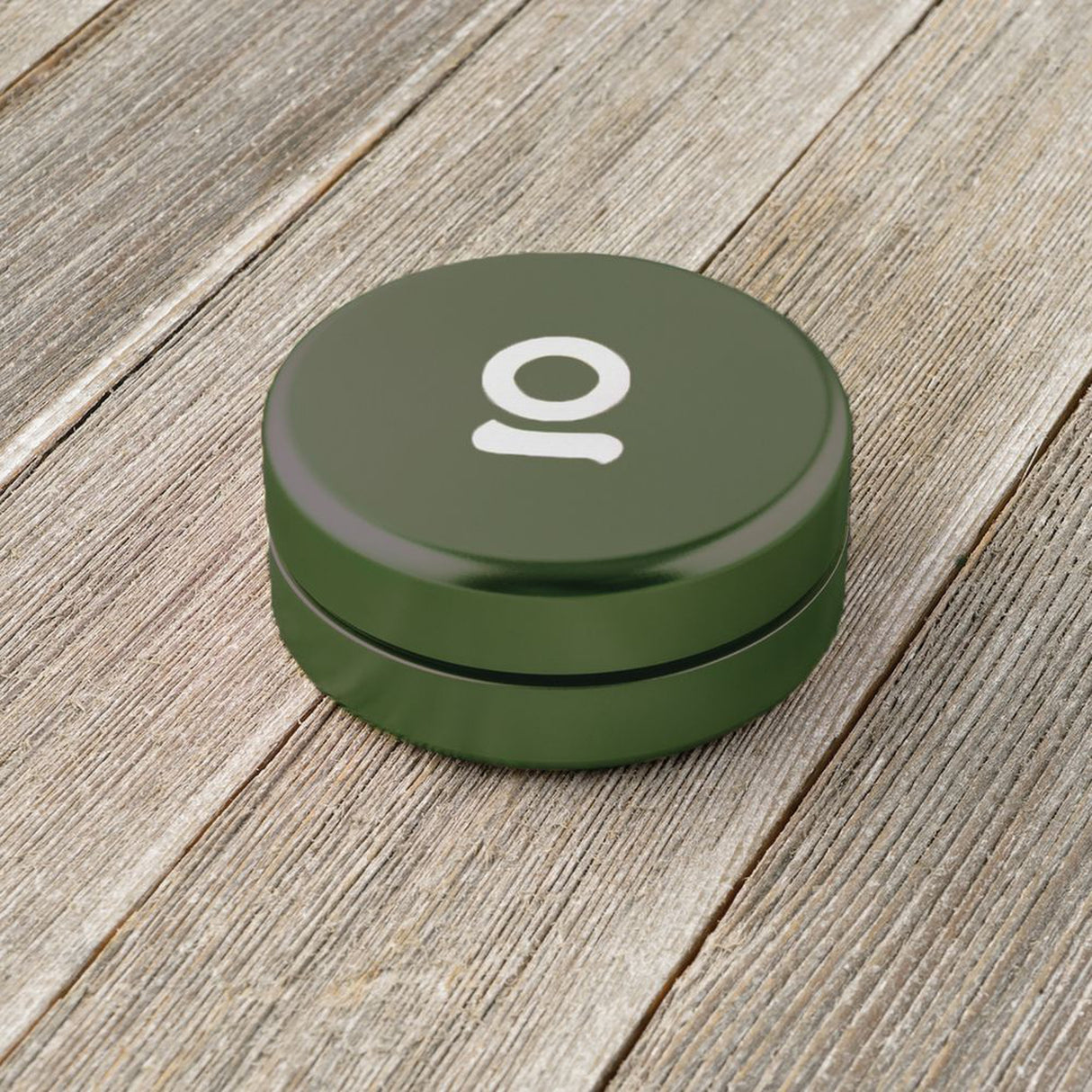 Aluminum Storage Puck on a wooden surface, featuring a round design with an airtight seal, ideal for discreet, pocket-sized storage of small items.