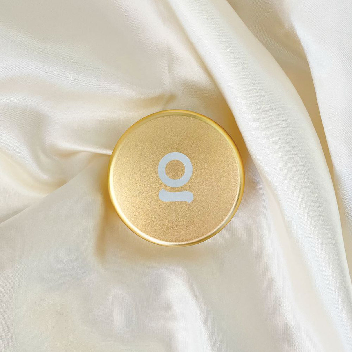 Aluminum Storage Puck with a white letter, featuring a round, gold design ideal for discreet, airtight storage of small items.