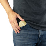 Person placing an Aluminum Storage Puck into a jeans pocket, highlighting its compact, discreet design for secure on-the-go storage.