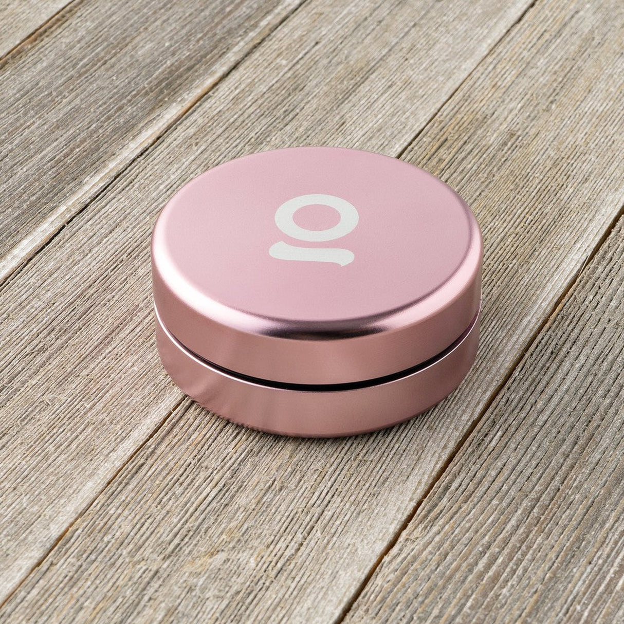 Aluminum Storage Puck on wood surface, featuring a round pink design with airtight seal, ideal for discreet storage. Compatible with Ongrok 4 Piece EZ Grinder.