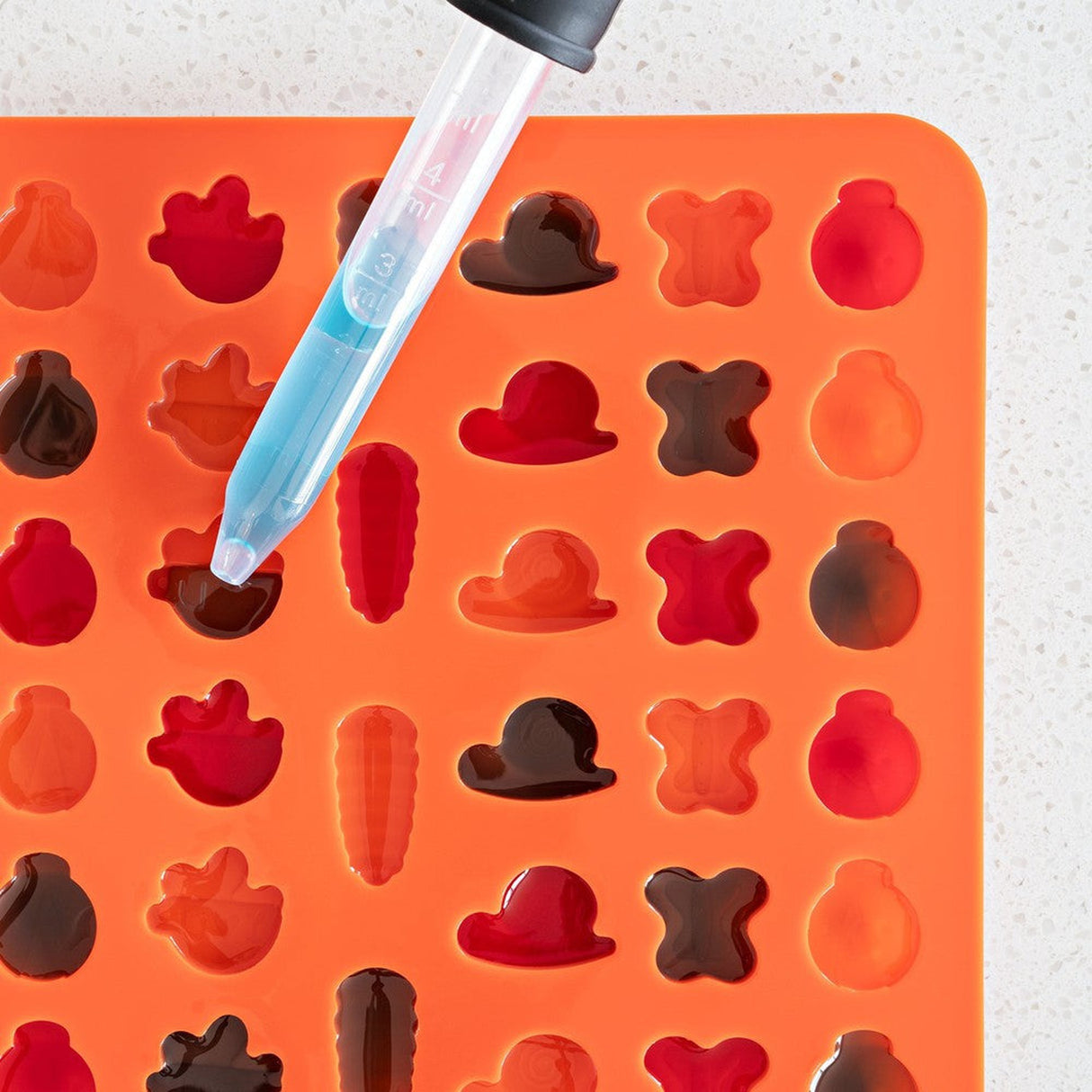 Silicone Gummy Molds & Dropper Kit - Set of 3, featuring a pipette over a tray of gummy candies, perfect for easy and mess-free edible creations.