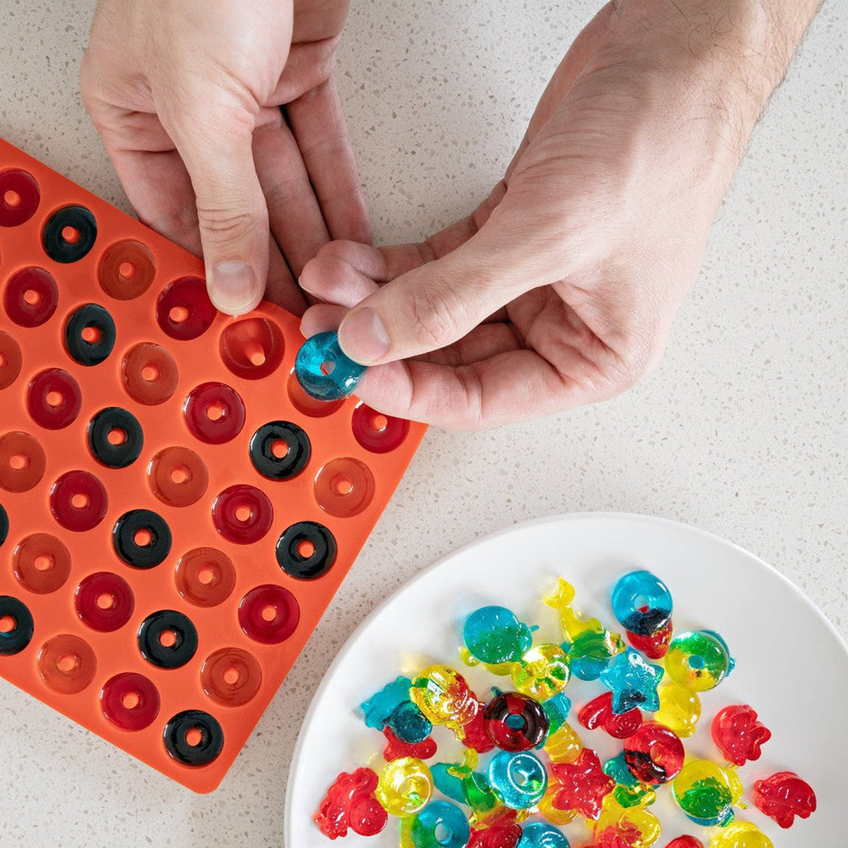 Silicone Gummy Molds & Dropper Kit - Set of 3, featuring a person using the dropper to place candy into a mold tray for easy candy creation.