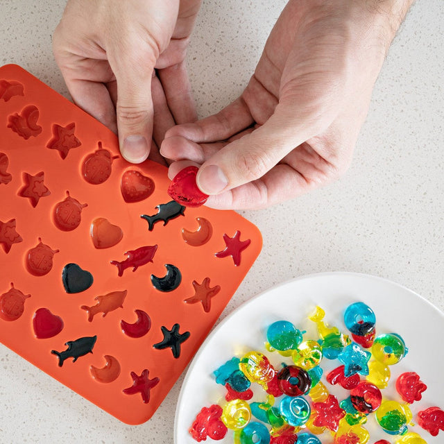 Person placing candy in Silicone Gummy Molds & Dropper Kit - Set of 3, highlighting non-stick, food-grade silicone making candy removal easy and mess-free.