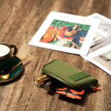 Smell Proof Water-Resistant Wallet shown on a wooden table, alongside a coffee cup and book, highlighting its compact, secure design with visible compartments and accessories.