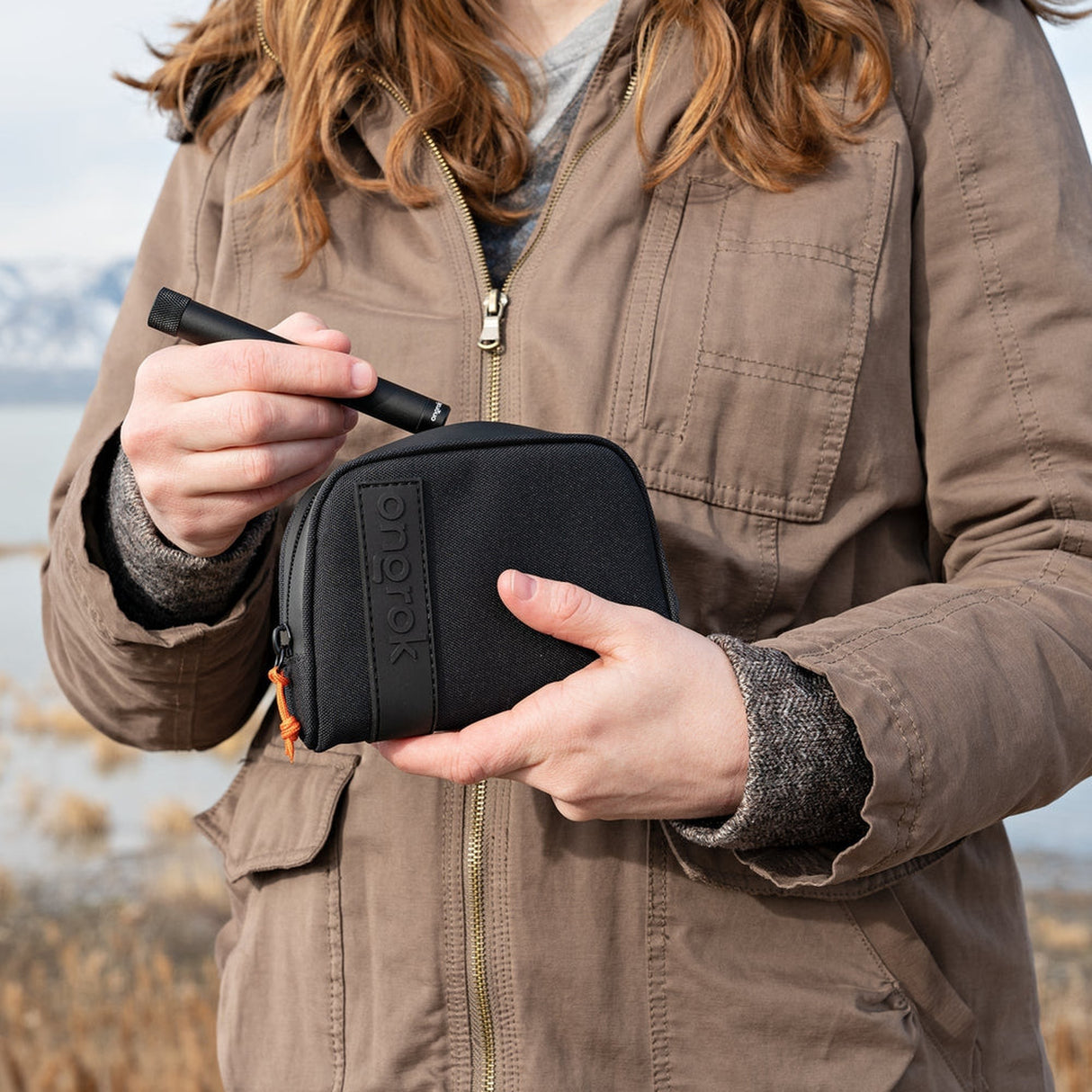 A woman holds the Smell Proof Water-Resistant Wallet, showcasing its compact design and secure zipper, ideal for odor-free storage and organization.