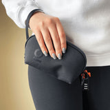 Hand holding the Smell Proof Water-Resistant Wrist Bag - Black, featuring a small black pouch with a detachable wrist strap and visible keychain.