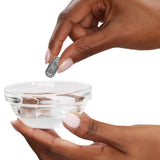 Hand holding a pill over a bowl, representing the PAX Maintenance Kit for efficient vaporizer cleaning, ensuring optimal performance and longevity of PAX devices.