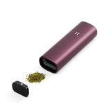 PAX Plus Dry Herb Vaporizer with a sleek design, featuring a white 'X' on its purple body, accompanied by a concentrate insert and round button.