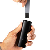 Hand holding PAX Prep Tongs, a black cylindrical stainless steel tool for vaping, featuring a silicone tamp and hidden tool for efficient flower management.