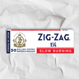 Zig-Zag 1 1/4 White Rolling Paper box on textured surface, showcasing premium thin-weight papers for smooth, slow-burning experiences with natural gum Arabic seal.