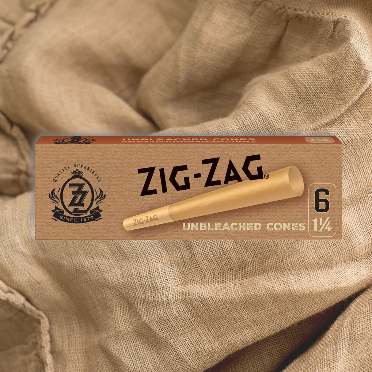 Pre Rolled Unbleached 1 1/4 Paper Cones - Pack of 6, displayed in a crush-proof slide box on a cloth surface.